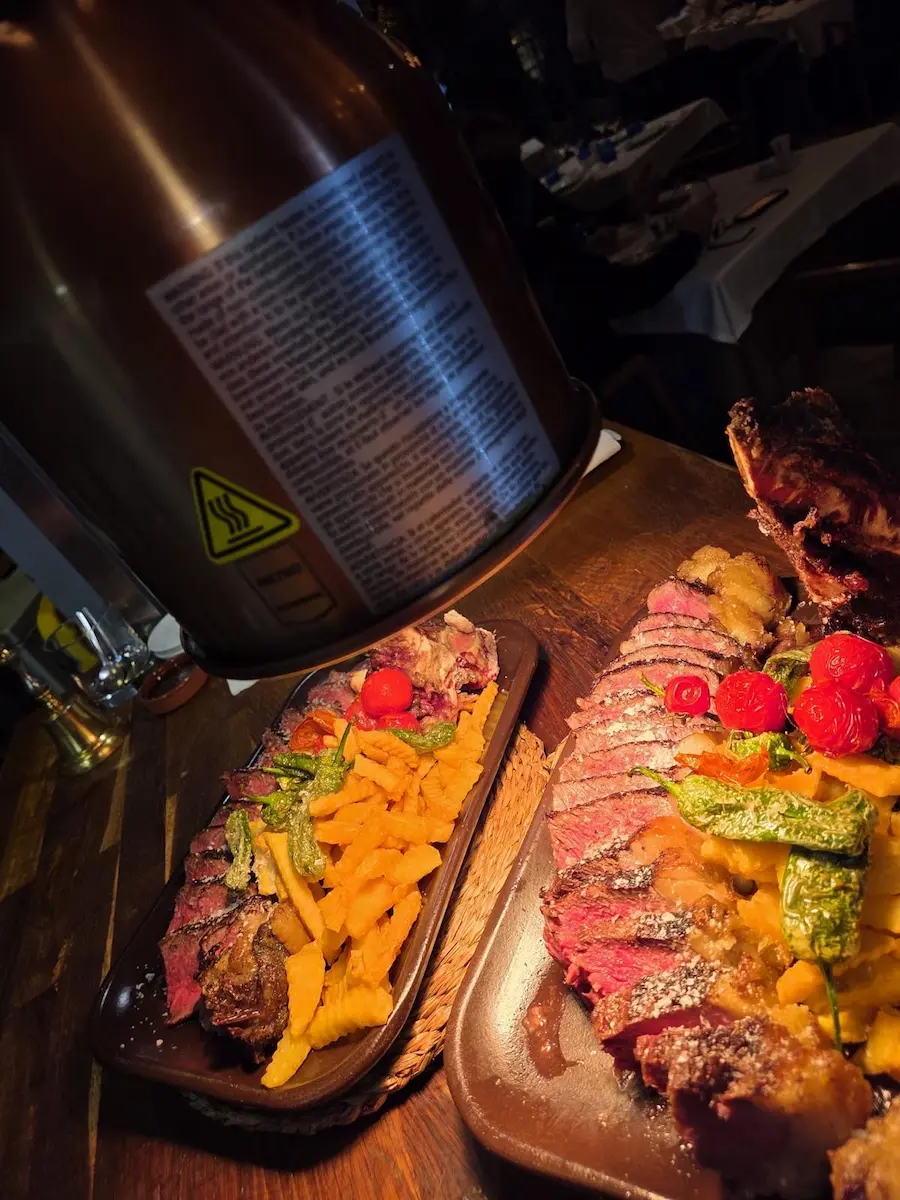 Plato de carne premium con patatas fritas y pimientos en asador uruguayo.