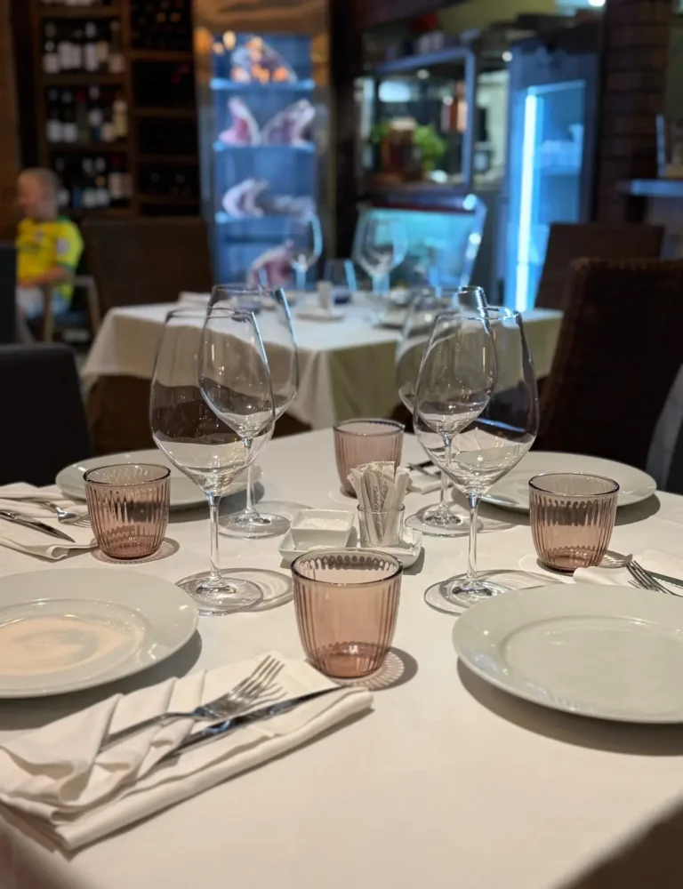 Mesa de restaurante con copas dispuestas cuidadosamente antes del servicio en un ambiente de parrilla uruguaya.